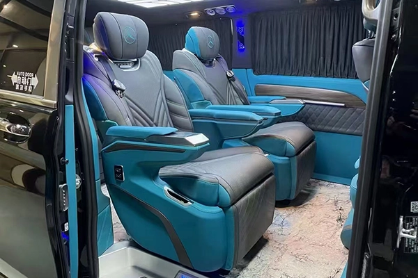 Two-tone blue gray leather captain seats installed in Mercedes van, with control armrest and ambient lighting