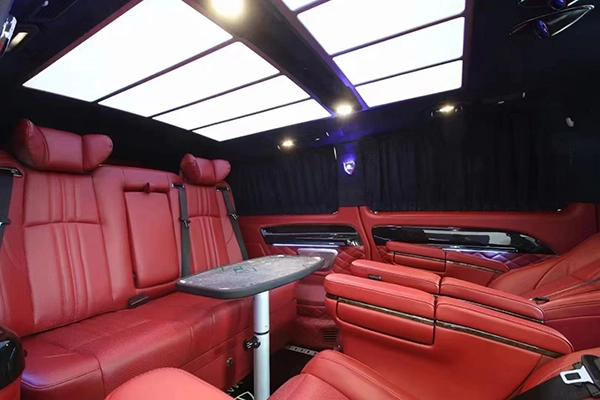 Full red leather car rear bench seat installed in van, matching captain seats with folding side table and LED ceiling lights