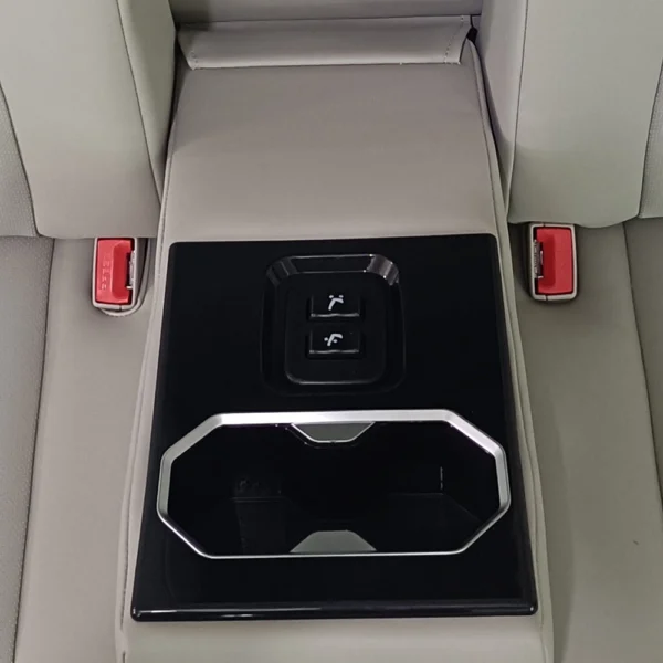 Close-up shot of car sofa bed pull-down armrest fitted with physical adjustment buttons and dual cup storage slot