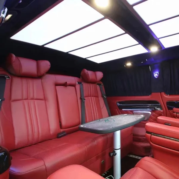 Real vehicle interior installation shot of red leather car sofa bed, matched with foldable table and luxury MPV ambient ceiling light