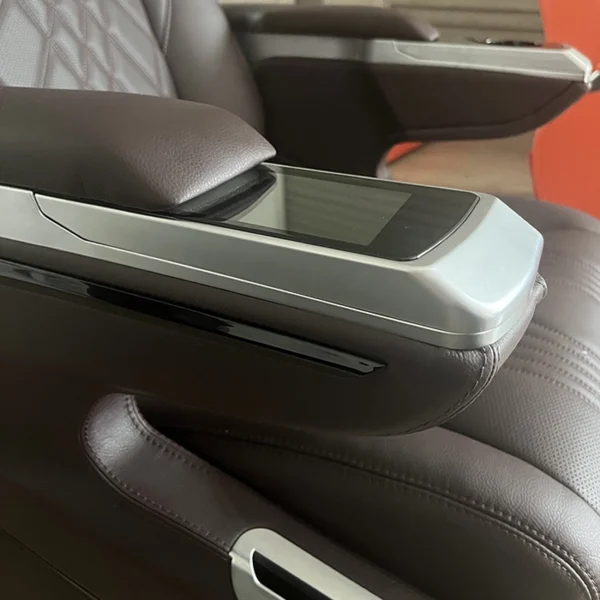 Close-up of a high-tech touch screen control panel integrated into the armrest of luxury car seats.