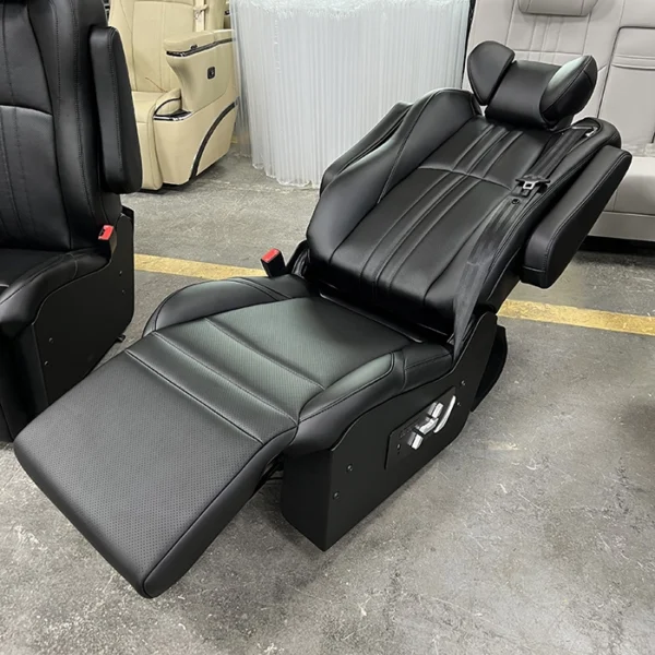 Black luxury van seats fully reclined, showcasing the electric leg rest and ergonomic flat-bed design
