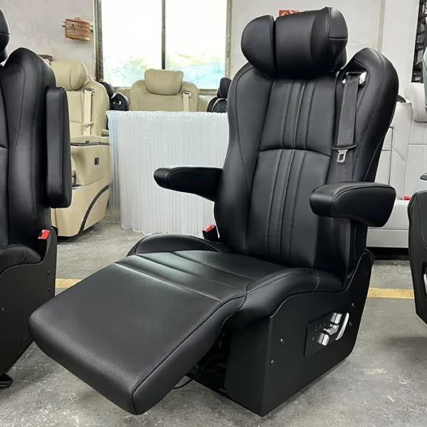 Factory angled shot of black leather luxury van captain seat, vertical perforated stitching, movable armrest, fully stretched electric leg rest and side physical control buttons