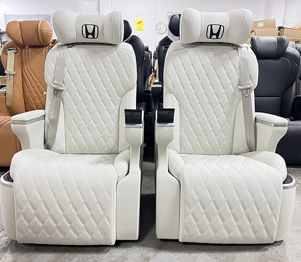 Front view of twin white leather Sienta captain seats with headrest Honda logo and touch screen armrest