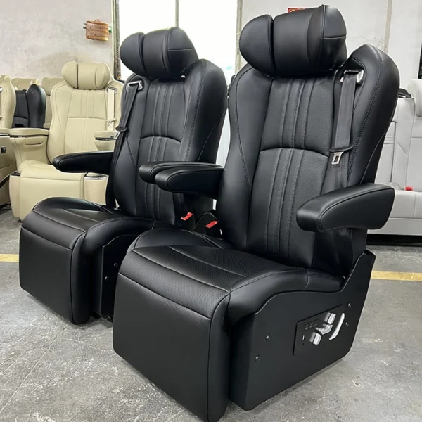 Two black perforated leather sprinter van captain seats, vertical stitching, retractable movable armrests, side physical control buttons and built-in safety seatbelts